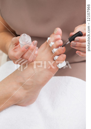 Pedicurist painting a customers nails 12107966