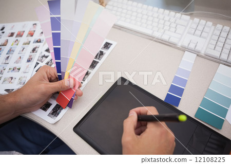 Designer using graphics tablet and colour charts 12108225