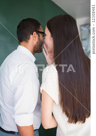 Businesswoman whispering into male colleagues ear 12108481