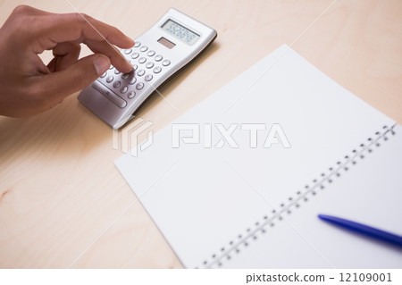 Hand using calculator at desk 12109001