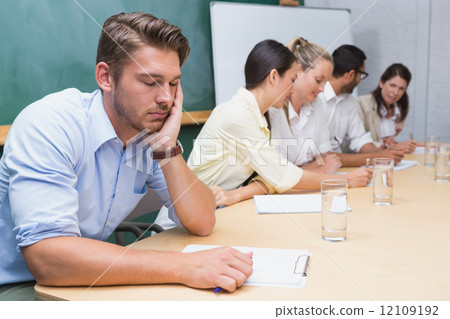 Buisness people working with man sleeping next to them 12109192