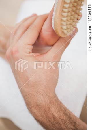 Pedicurist brushing customers foot 12109516