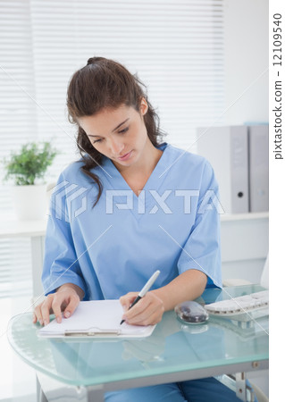 Brunette doctor writing on clipboard 12109540