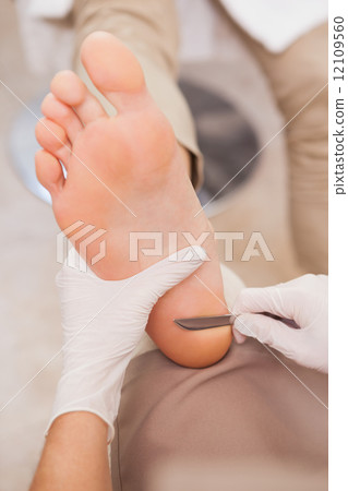 Pedicurist removing dead skin 12109560