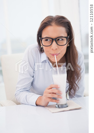 Pretty businesswoman drinking milk at her desk 12110558