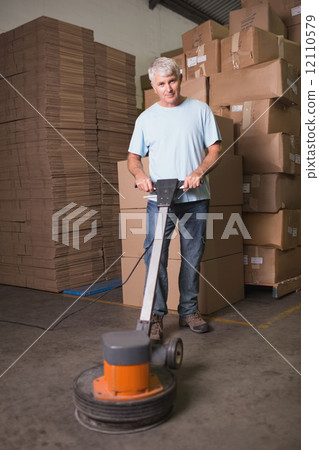 Man cleaning warehouse floor with machine 12110579