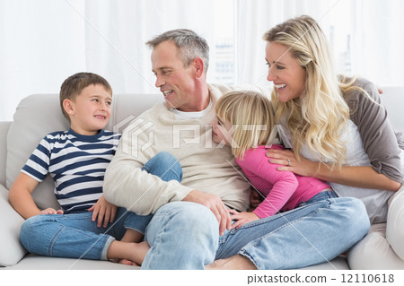 Smiling family sitting on sofa 12110618
