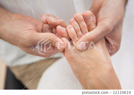 Pedicurist massaging customers foot 12110619