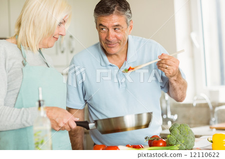 Happy mature couple making dinner together 12110622