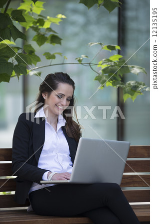 Businesswoman using a laptop outdoors. Businesswoman using a laptop outdoors. 12135195