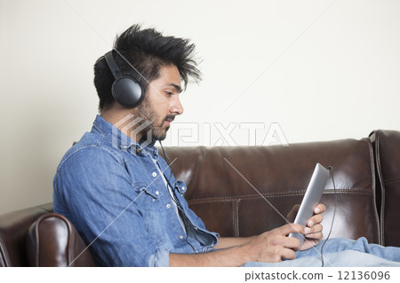 Indian man using digital tablet at home. 12136096
