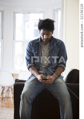 Indian Man using his phone at home. Indian Man using his phone at home. 12136120