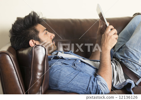 Indian man using digital tablet at home. Indian man using digital tablet at home. 12136126