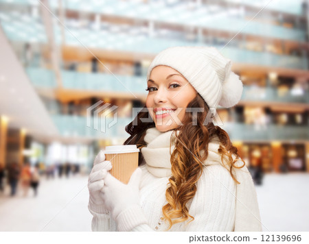 smiling young woman in winter clothes with cup 12139696