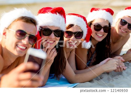group of friends in santa hats with smartphone 12140930
