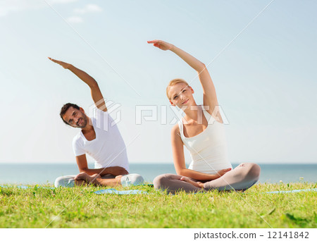 smiling couple making yoga exercises outdoors 12141842