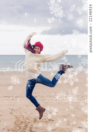 Composite image of woman in stylish warm clothing jumping at bea 12146914