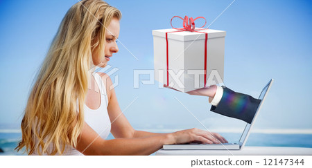 Composite image of pretty blonde using her laptop at the beach 12147344