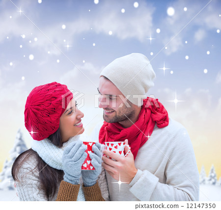 Composite image of winter couple holding mugs 12147350