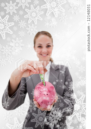 Composite image of money being put into piggy bank by smiling ba Composite image of money being put into piggy bank by smiling ba 12148031