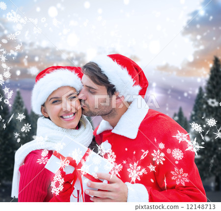 Composite image of festive young couple holding gift 12148713