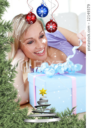 Cheerful blond woman holding a present lying on the floor Cheerful blond woman holding a present lying on the floor 12149379