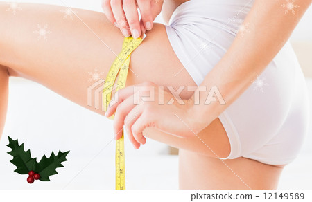 Composite image of toned woman measuring her thigh Composite image of toned woman measuring her thigh 12149589