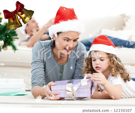 Mother and daughter unwrapping a present lying on the floor 12150107