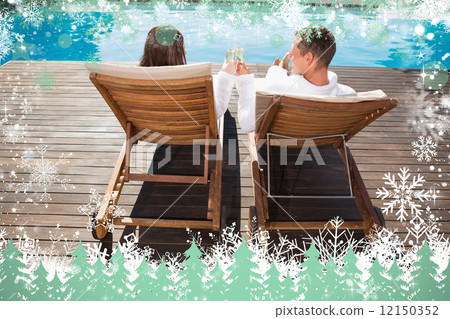 Couple toasting champagne by swimming pool 12150352