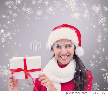 Composite image of festive brunette holding gift 12151107