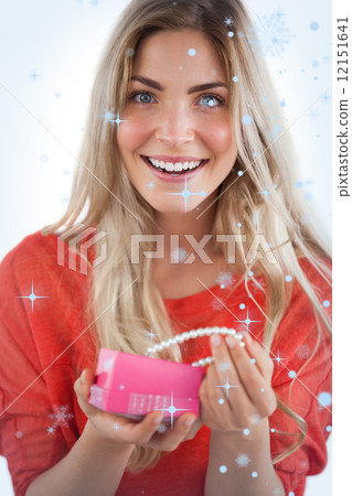 Composite image of cheerful woman discovering necklace in a gift box 12151641