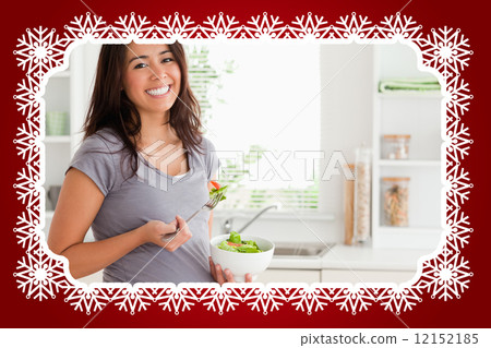 Attractive pregnant woman holding a bowl of salad while standing 12152185