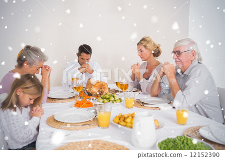 Composite image of family saying grace before eating a turkey 12152390