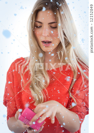 Composite image of surprised woman opening her gift Composite image of surprised woman opening her gift 12152849