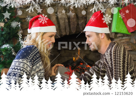 Man gifting woman in front of lit fireplace during christmas 12153620