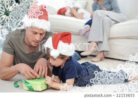 Father and son unwrapping a present lying on the floor 12153655
