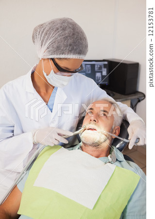Dentist examining a patients teeth in the dentists chair 12153781