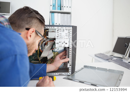Computer engineer working on broken console with screwdriver 12153994