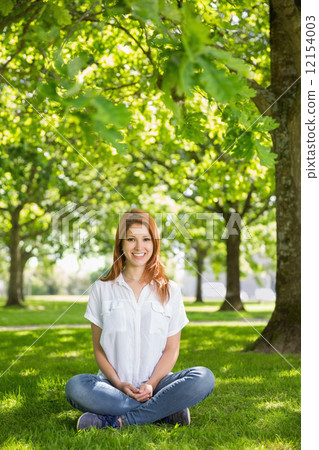 Pretty redhead smiling at camera in the park Pretty redhead smiling at camera in the park 12154003