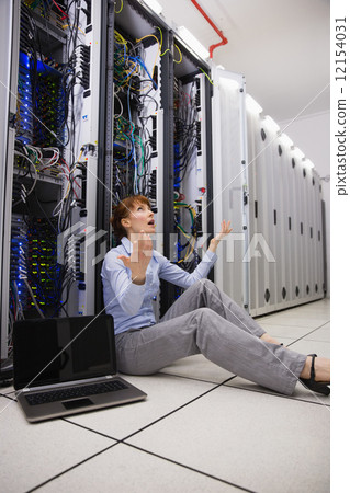 Stressed technician sitting on floor beside open server Stressed technician sitting on floor beside open server 12154031