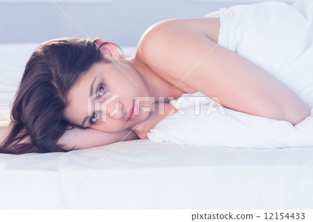 Beautiful brunette lying on bed smiling at camera 12154433