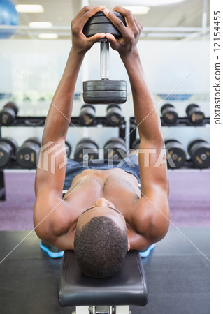 Shirtless man exercising with dumbbell in gym 12154455