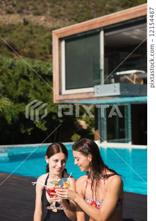 Women holding drinks by swimming pool Women holding drinks by swimming pool 12154487