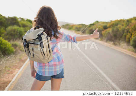 Woman hitchhiking on countryside road 12154653