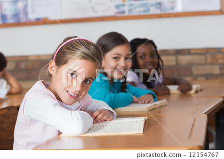 Cute pupils reading books at their desks Cute pupils reading books at their desks 12154767