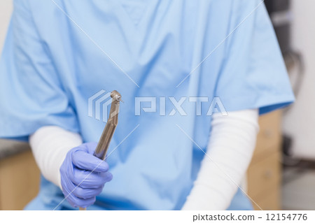 Dentist in blue scrubs holding dental drill Dentist in blue scrubs holding dental drill 12154776