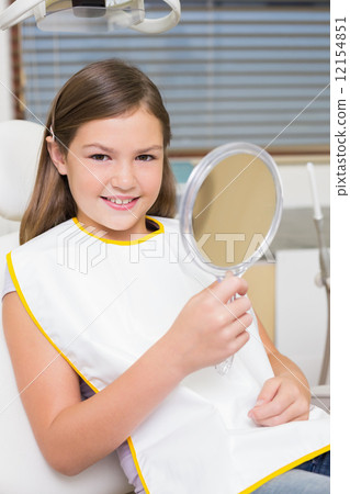 Little girl holding mirror in dentists chair 12154851