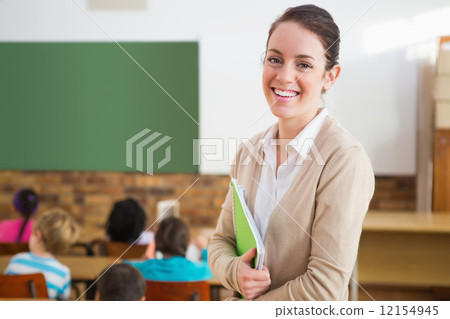 Pretty teacher smiling at camera at back of classroom