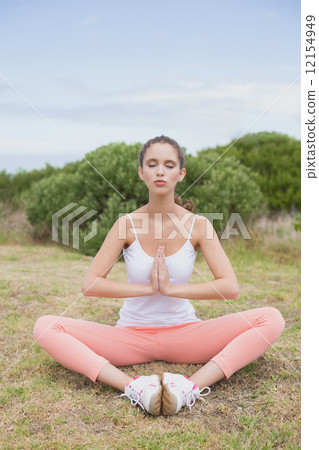 Woman with hands joined sitting on countryside landscape 12154949
