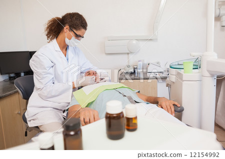 Dentist examining a patients teeth in the dentists chair 12154992